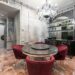 Interior of modern spacious kitchen with round table and red chairs placed near contemporary counter with kitchenware in stylish apartment