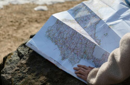 A person studies a roadmap placed on a rock, embraced by natural sunlight outdoors.
