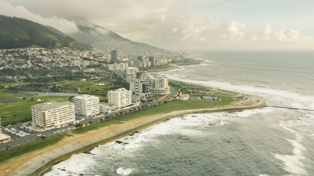 A breathtaking aerial view of Cape Town's coastline and urban landscape under a cloudy sky.